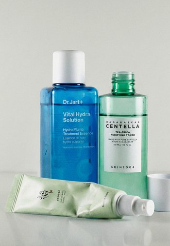 Tre prodotti per la cura della pelle: bottiglia Dr.Jart+ blue Vital Hydra Solution, tonico Skin1004 verde Madagascar Centella e un tubetto di crema verde chiaro.