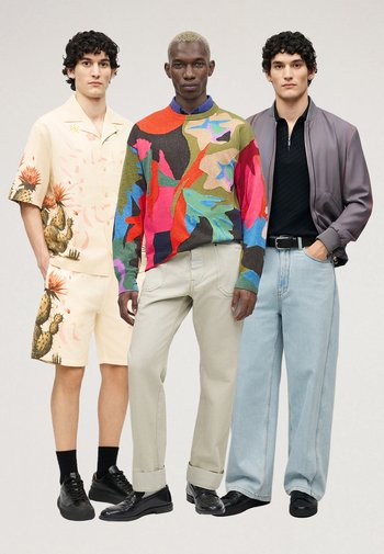 Drie mannen staan zij aan zij in modieuze outfits: set shorts met cactusprint, kleurrijke abstracte trui met beige broek, en grijze bomberjas met jeans.