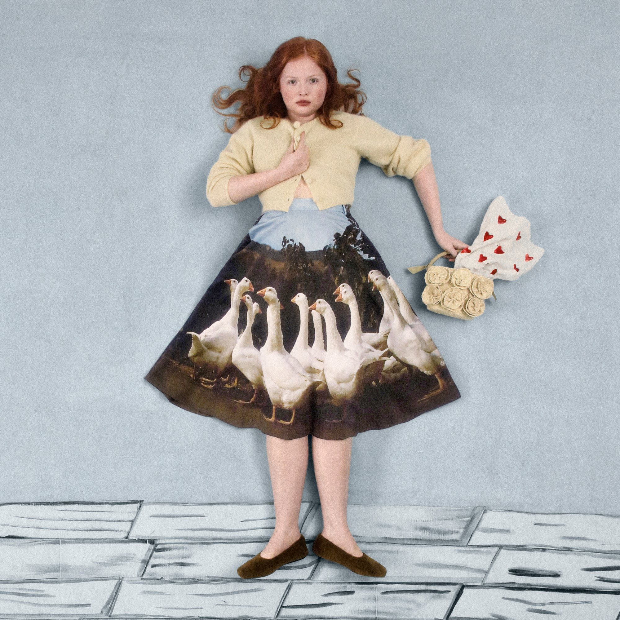 Girl with red hair in a cream cardigan and a printed skirt depicting geese, holding a bag of roses against a light blue background.