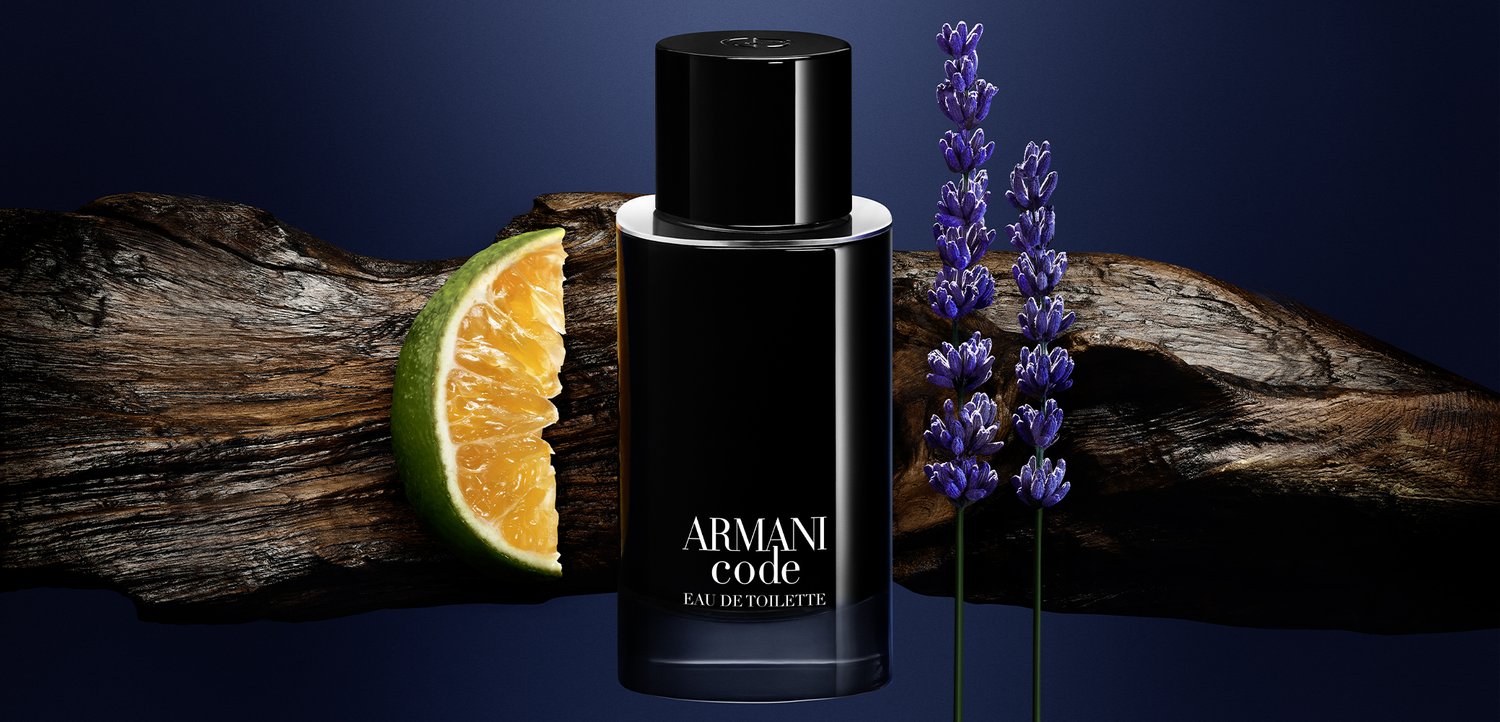 Flacon d’Armani Code Eau de Toilette avec du bois, des brins de lavande et un agrume tranché sur un fond bleu foncé.