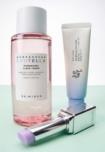 Madagascar Centella toner, Koreaanse SPF50+ PA++++ zonnebrandcrème en zilveren tube lavendelkleurige kleurcorrigerende balsem op een lichtgroen oppervlak.