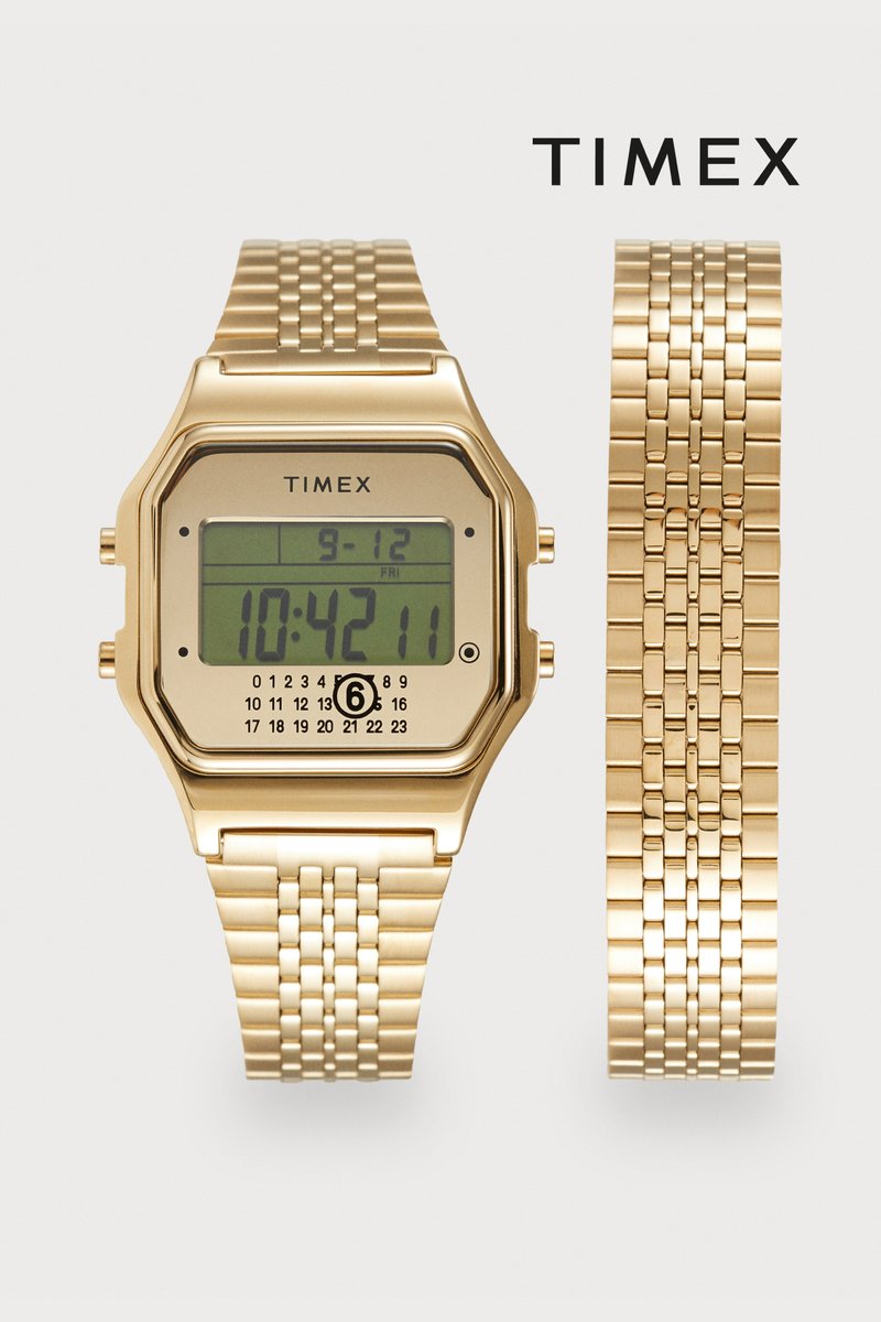 Digital Timex-ur med kasse i guldtonet metal og flettet ledarmbånd. Har en LCD-skærm, der viser tid og dato. Tyndt og rektangulært design.