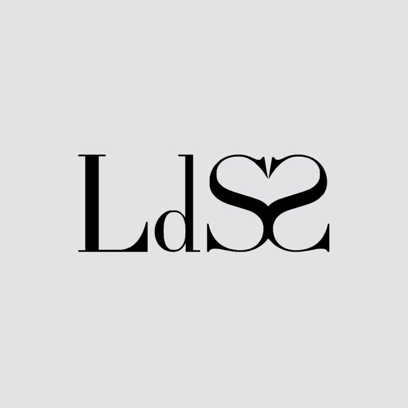 Il testo stilizzato "LdS" presenta una forma a cuore nella lettera "S", su uno sfondo grigio chiaro. Design minimalista e moderno.