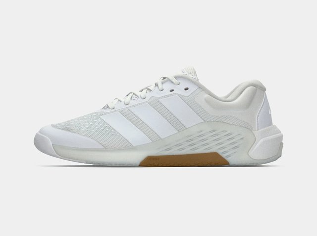 Zapatilla deportiva blanca de perfil bajo con parte superior de malla, tres rayas de Adidas, cierre de cordones y una sección de suela de goma color caramelo para tracción.