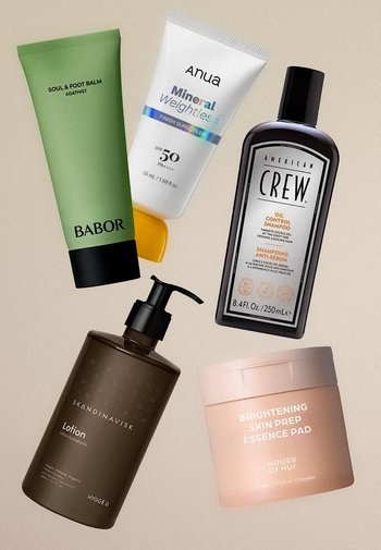 Cinq produits de soin de la peau et des cheveux comprenant un baume vert pour les pieds, un tube de crème solaire blanche, une bouteille de shampooing noire, une pompe à lotion marron et un pot rose de tampons éclaircissants.