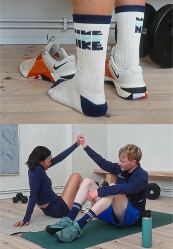 Scarpe da ginnastica Nike in arancione smorzato e bianco con accenti grigi. Calzini bianchi con strisce blu navy, con la scritta "LIFE LIKE." Sfondo in legno.