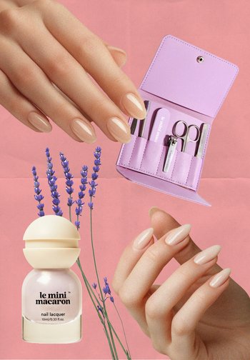 Bouteille de vernis à ongles beige avec un capuchon arrondi, trousse de soins pour les ongles rose avec outils, brins de lavande, et main manucurée affichant des ongles allongés.