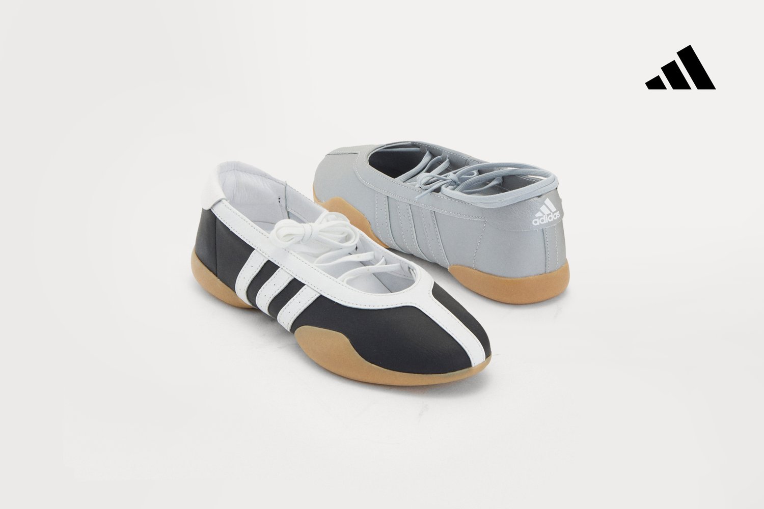 Two pairs of trainers: one black and white with three stripes, the other in grey. Both have rubber soles and are set against a light background.