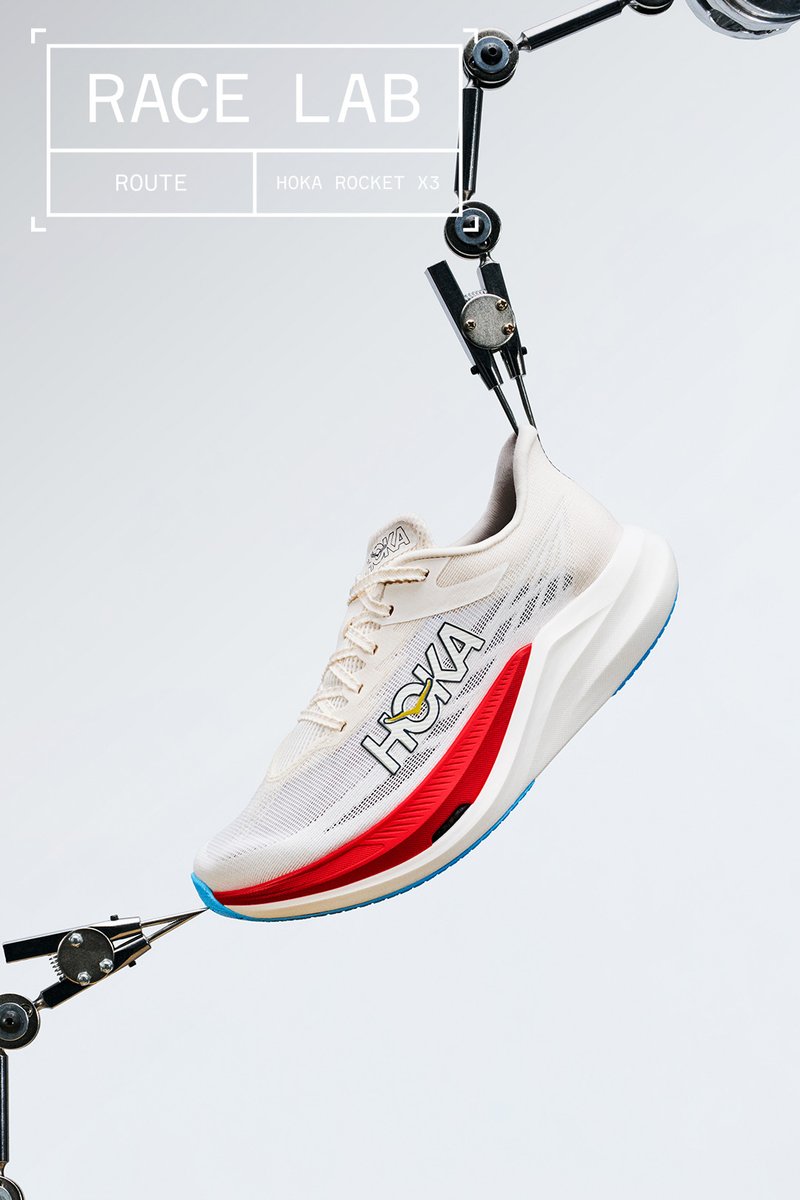 Chaussure de course Hoka Rocket X3 blanche et rouge tenue par des bras mécaniques sur un fond clair uni, avec superposition de texte "Race Lab".