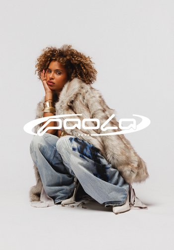 Manteau en fausse fourrure gris clair avec des bandes sombres, associé à un jean bleu déchiré avec un motif floral sombre et des bottes blanches à talons.