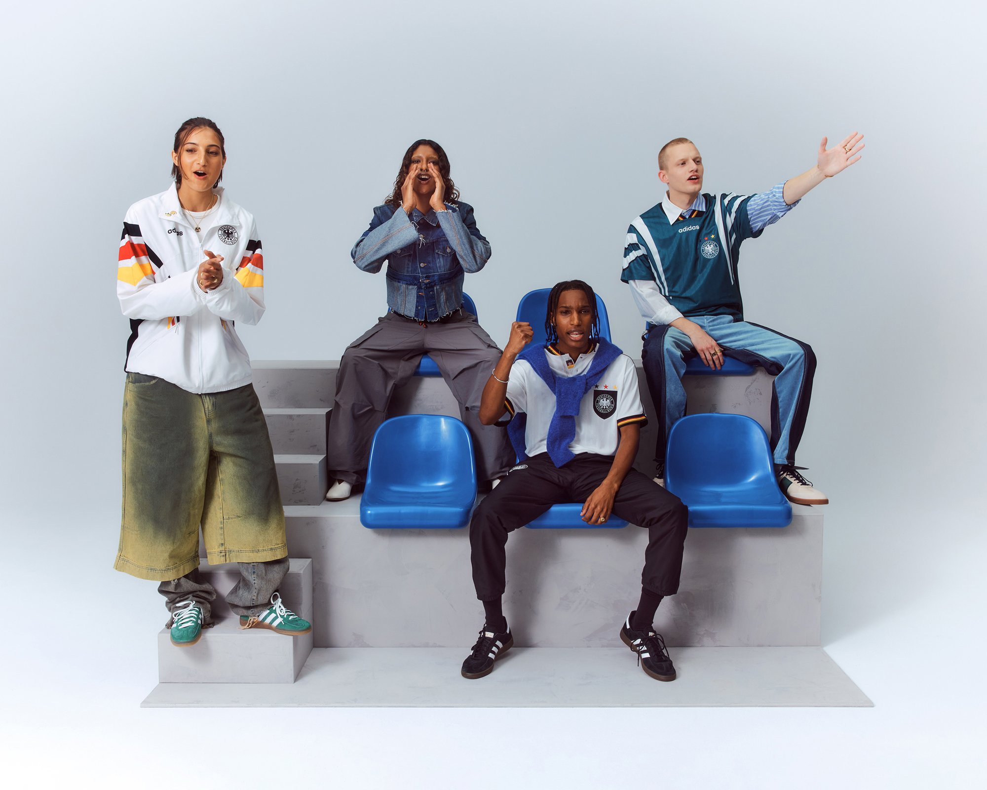 Quattro individui diversi in abbigliamento sportivo alla moda posano su sedili blu, esprimendo entusiasmo e coinvolgimento in un ambiente vivace.