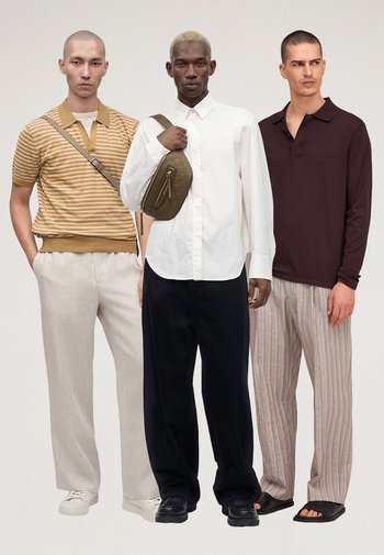 Drei Männer stehen nebeneinander und tragen legere Outfits: gestreiftes Polo mit Umhängetasche, weißes Hemd mit olivgrüner Umhängetasche und dunkles Langarmshirt mit gestreiften Hosen.
