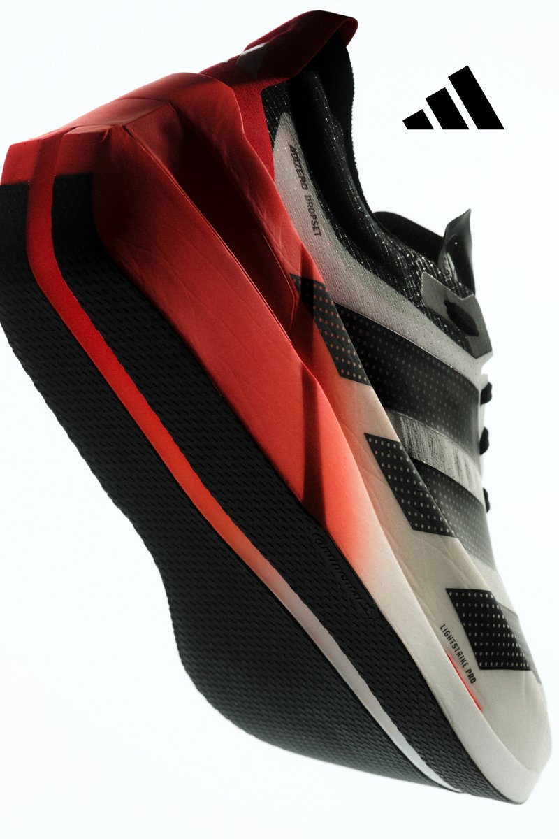 Schwarz-weißer Adidas Laufschuh mit roten Sohlenakzenten, nach oben geneigt, zeigt Logo und "Lightstrike Pro" Text an der Seite.