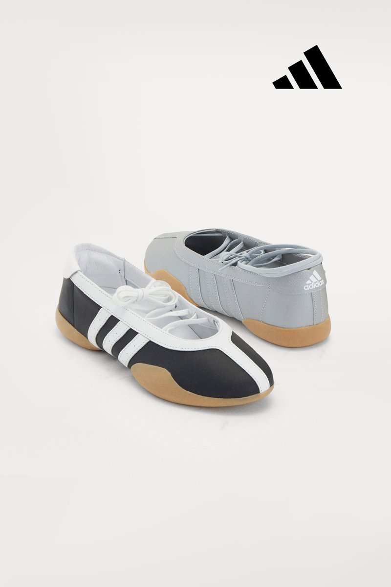 Scarpe Adidas in bianco e nero con suole in gomma, abbinate a scarpe grigie chiare, esposte su uno sfondo semplice.