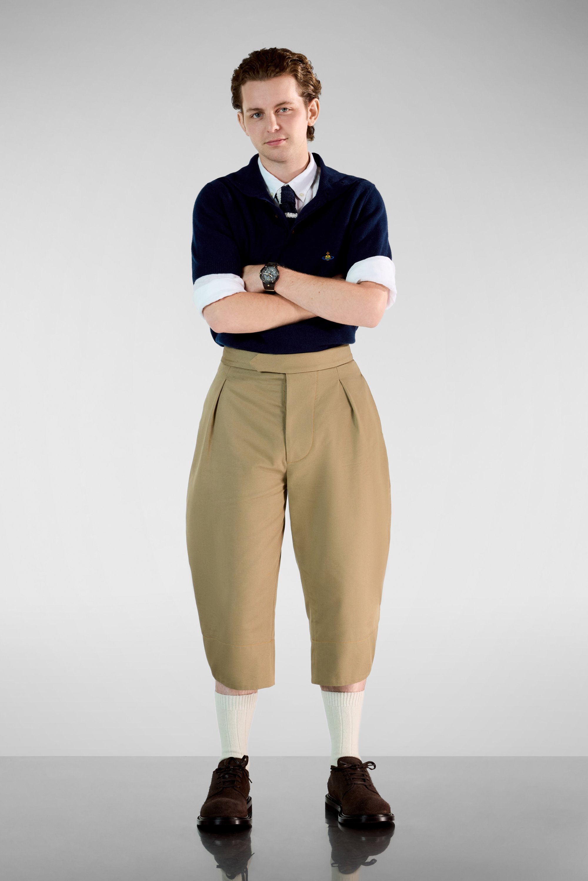 Pólder de cortas de marina, pantalones capri plisados en caqui, calcetines de tripulación blancos y zapatos marrones con cordones. Diseño simple con colores contrastantes.