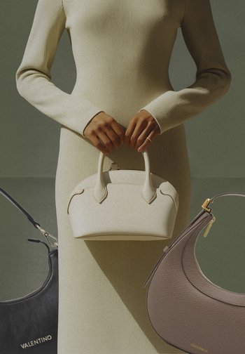 Osoba v béžových rebrovaných šatách drží malú bielu kabelku, pričom blízko sú vystavené čierna kabelka Valentino a hnedá kabelka Coccinelle.