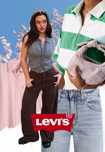 Frau in braunen Jeans und grauem ärmellosem Oberteil mit Kirschblüten, pinkem Hemd, grün-weiß gestreiftem Oberteil, pinker Tasche und Levi’s-Logo.