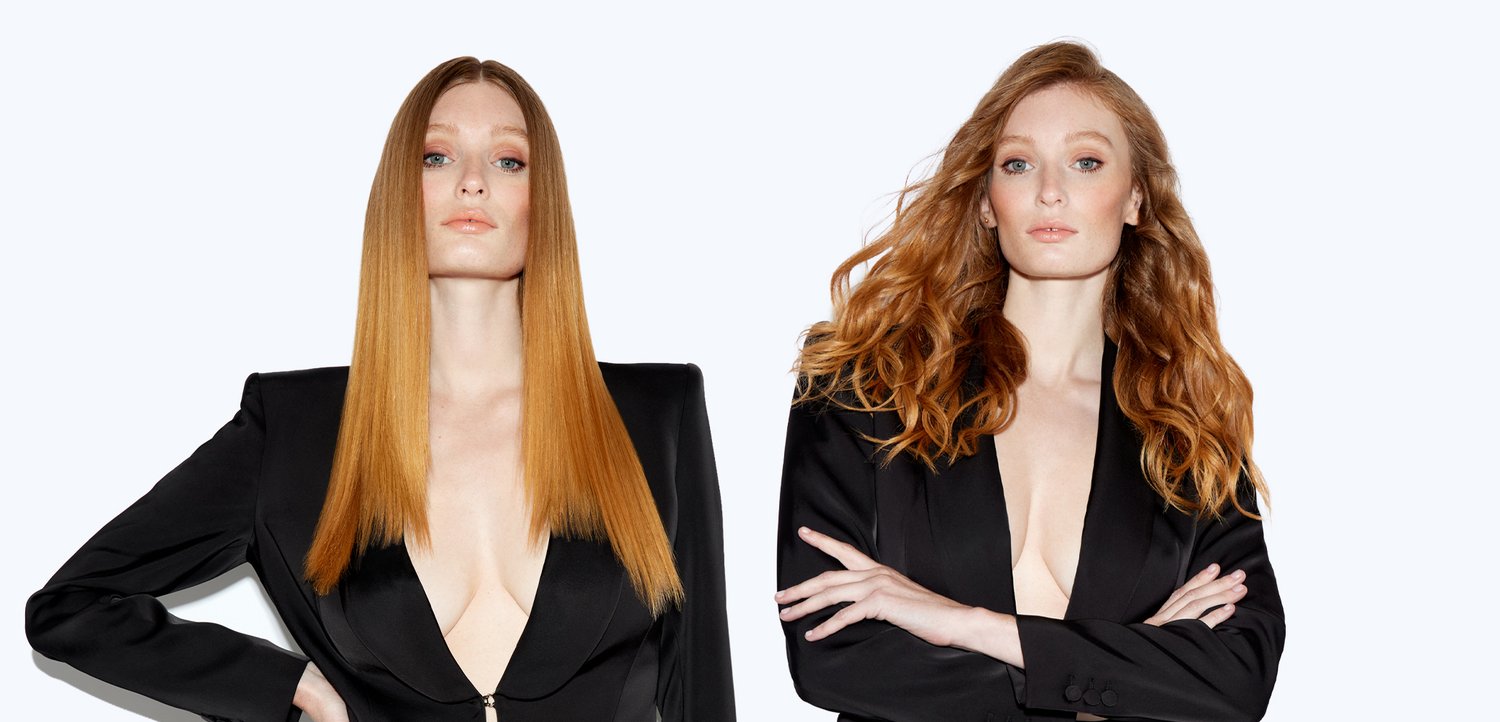 Deux femmes aux cheveux rouges portant des blazers noirs posent avec assurance sur un fond blanc uni, l'une avec les cheveux raides, l'autre ondulés.