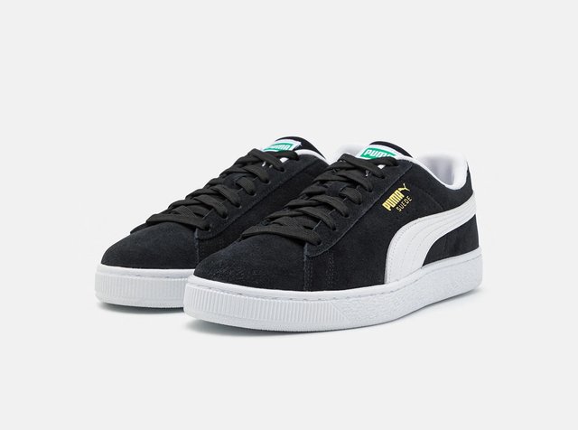 Paire de baskets Puma Suede noires avec semelle blanche et bande, lacets noirs, et logo doré sur le côté sur fond blanc.