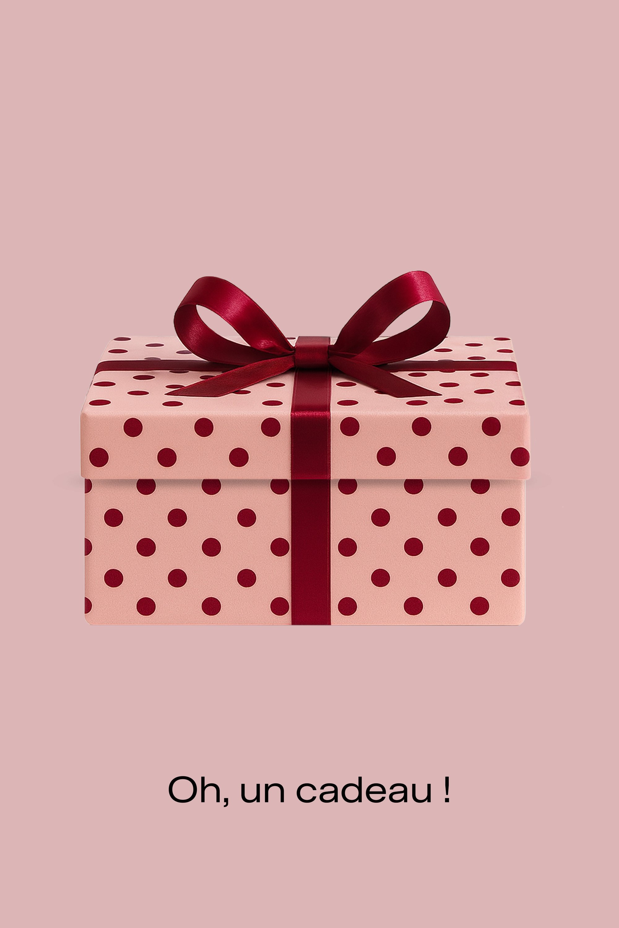 Boîte cadeau rose à pois rouges, nouée avec un ruban de satin bordeaux, posée sur un fond rose clair. Le texte en dessous indique : « Oh, un cadeau ! »