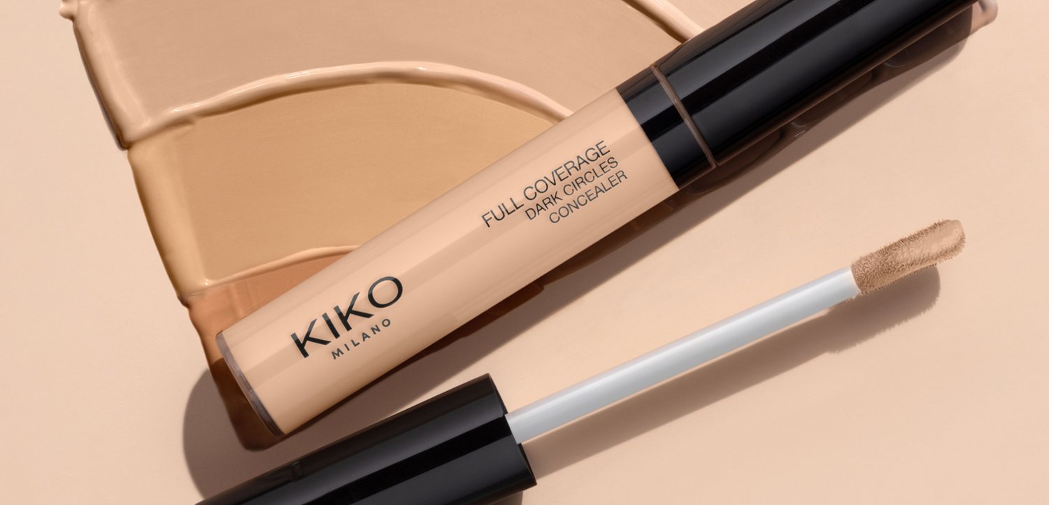 KIKO Milano full coverage dark circles concealer with applicator wand, placed on beige background with two shade swatches.
