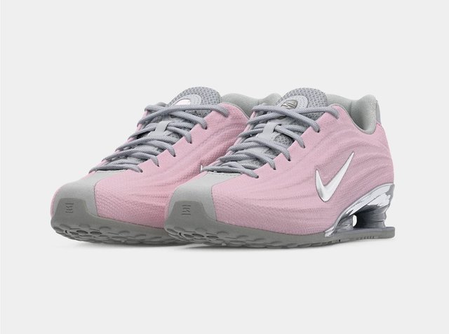 Par de zapatillas Nike de color rosa y gris con el logo swoosh blanco, cordones grises y suelas acolchadas, colocadas lado a lado sobre fondo blanco.