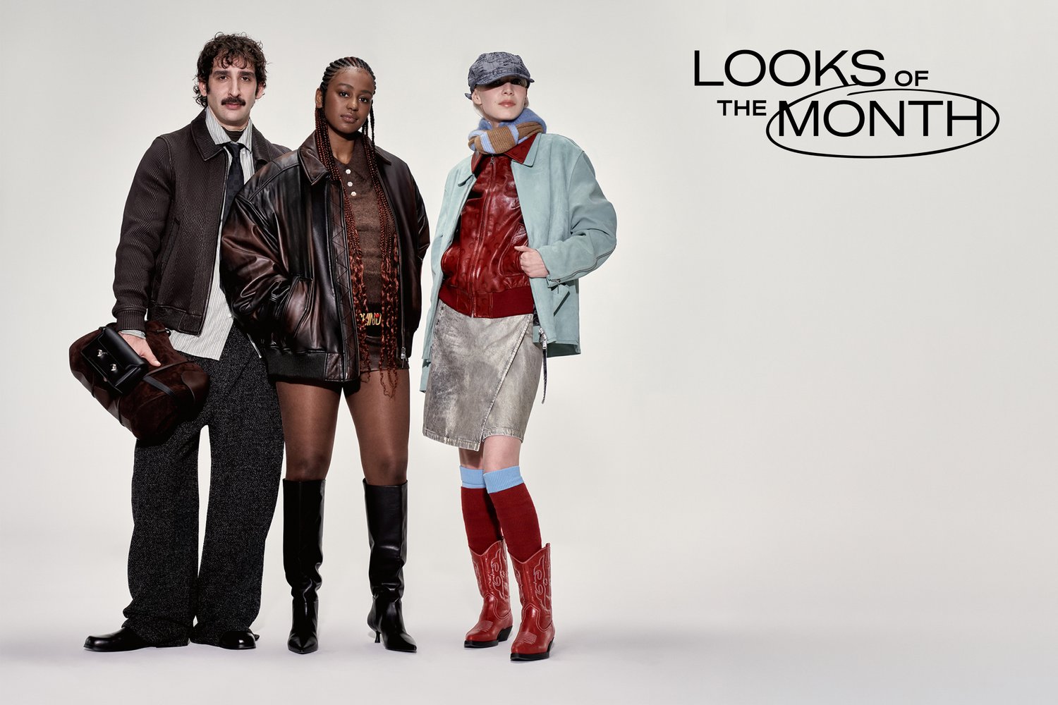 Drei Modelle posieren vor einem schlichten Hintergrund und zeigen verschiedene Outfits: ein Mann in einer braunen Jacke, eine Frau in einem Ledermantel und eine weitere in einer mintfarbenen Jacke.