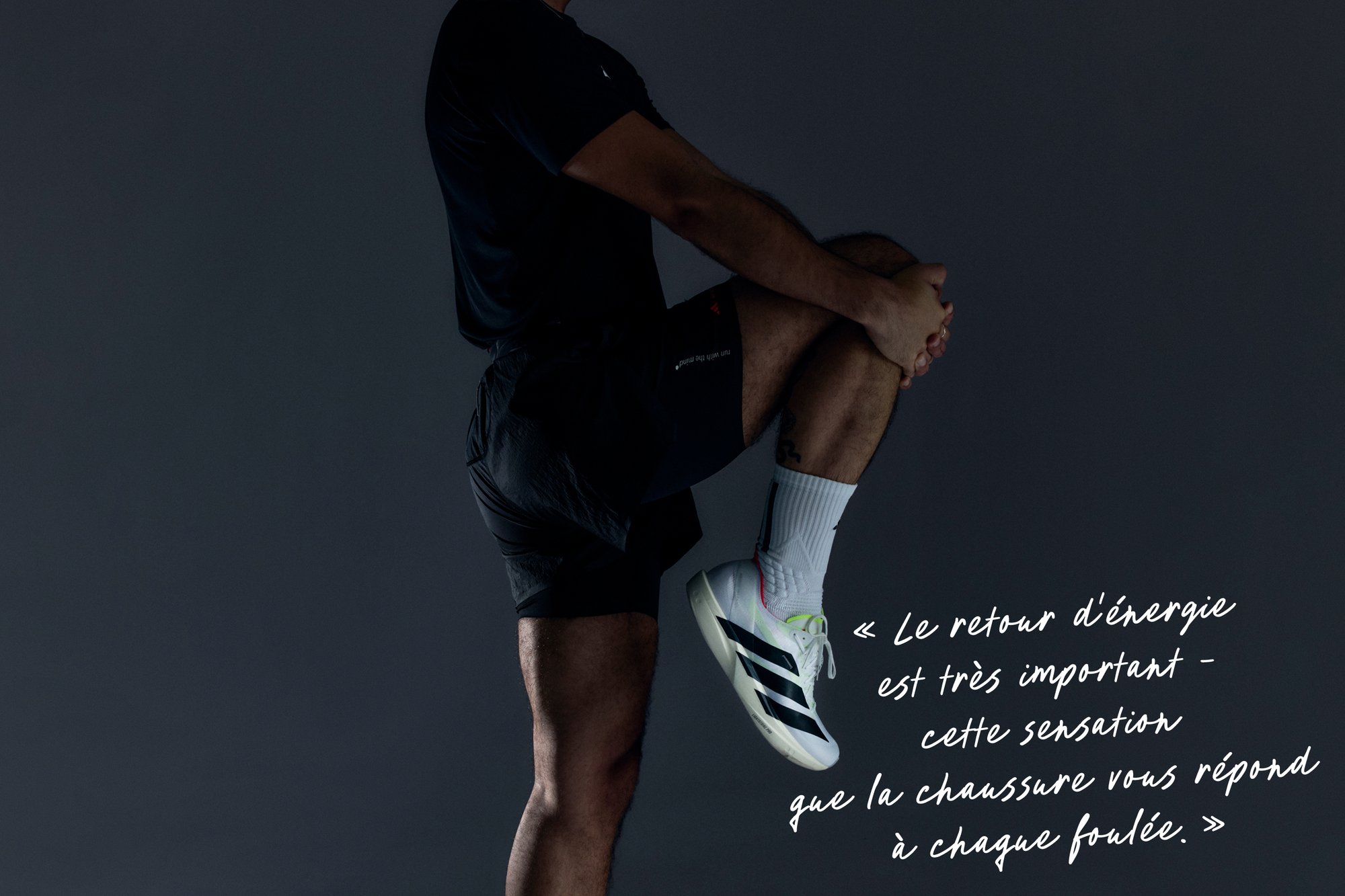 Chaussure de sport blanche avec des accents noirs et un bord rose clair. La chaussure présente un matériau supérieur texturé et une semelle rembourrée.