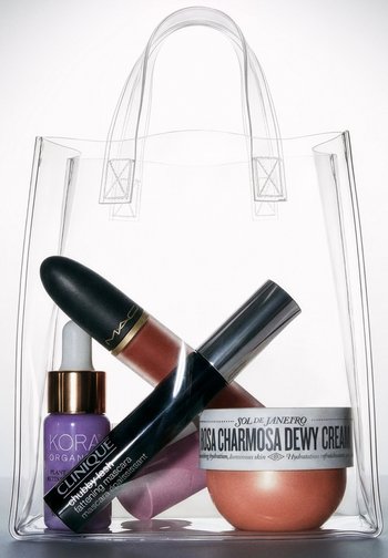 Borsa a tracolla trasparente contenente mascara Clinique, rossetto MAC, siero biologico KORA e barattolo di crema dewy Sol de Janeiro Rosa Charnosa.