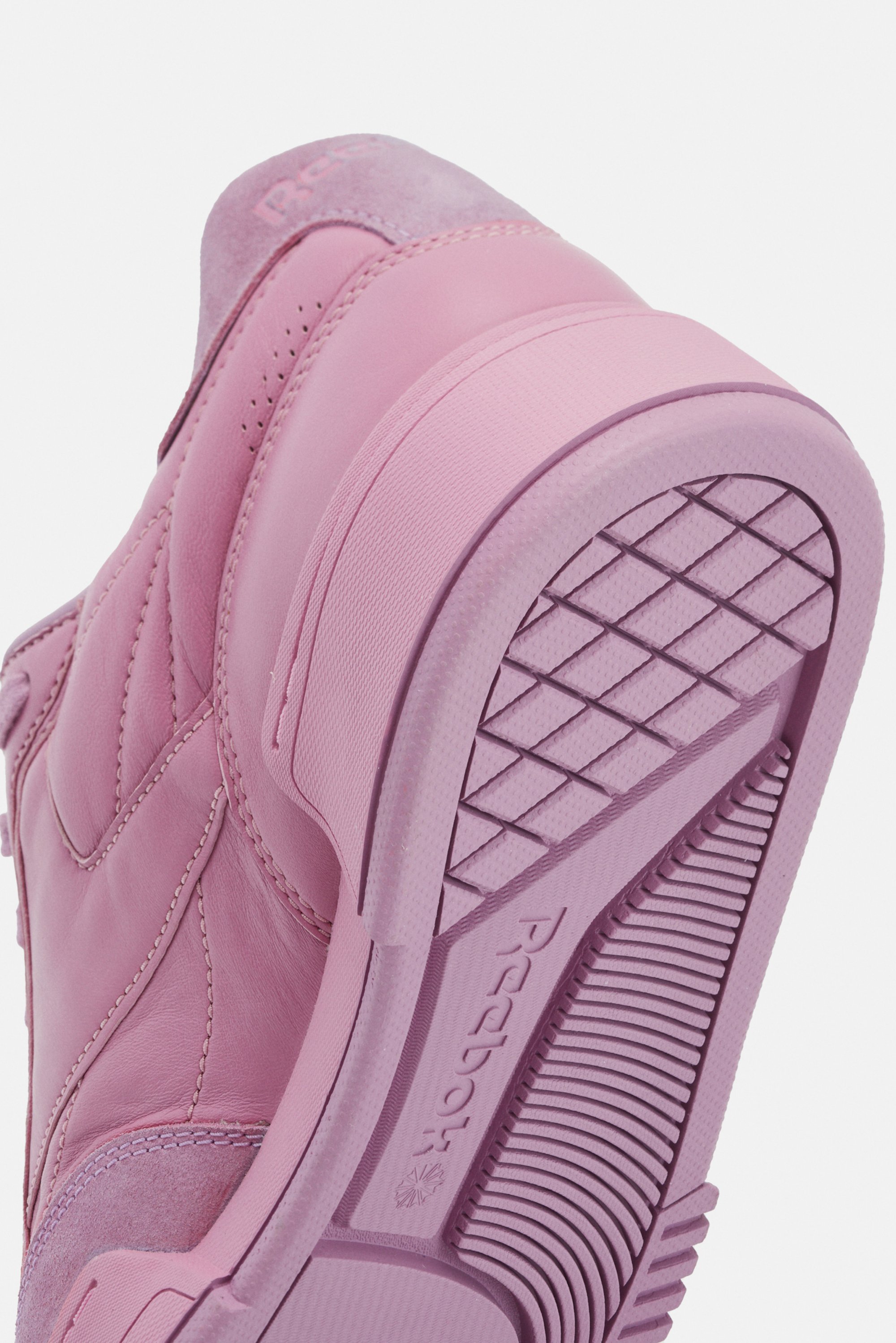 Close-up of a pink sneaker, highlighting the textured sole and smooth upper material with subtle stitching details.