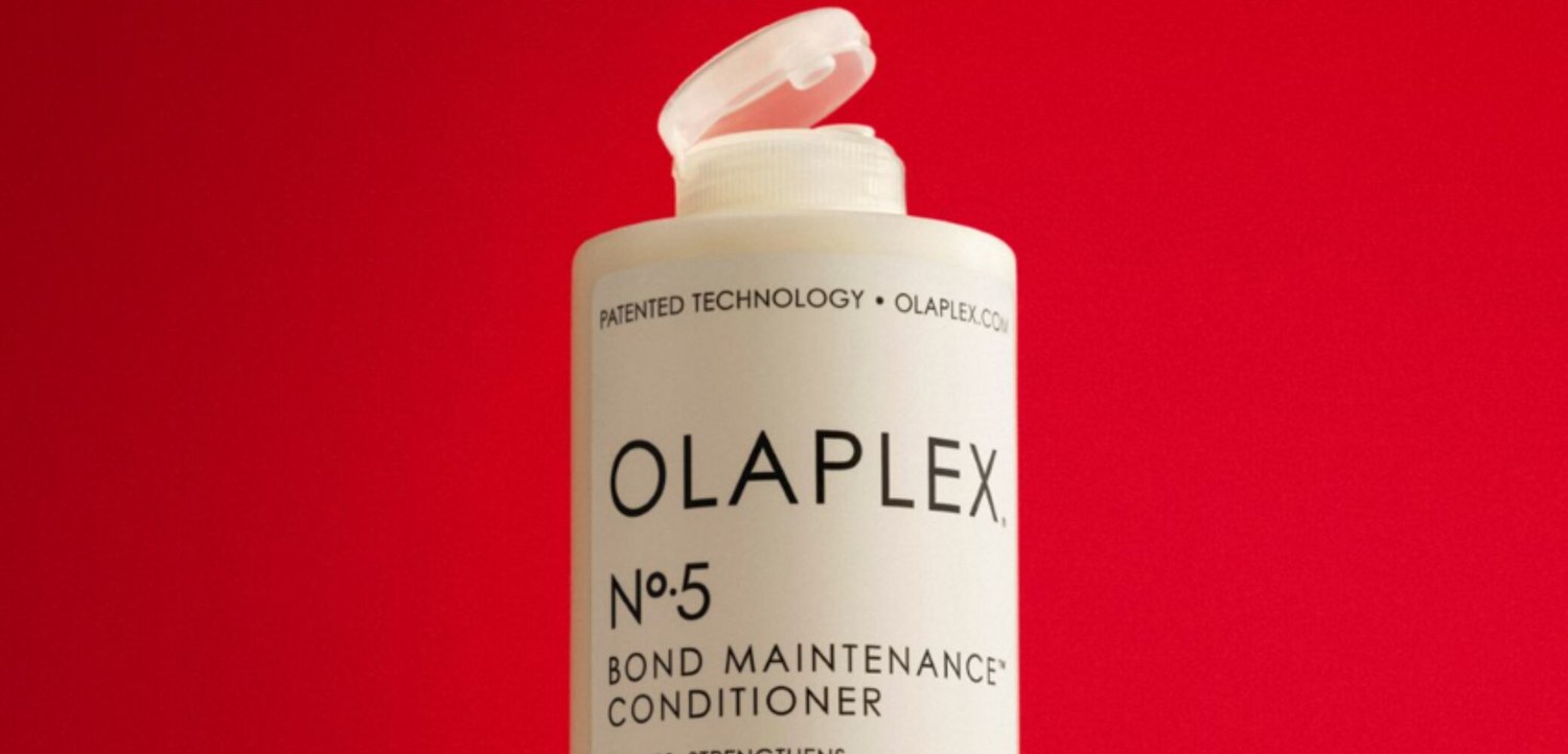 Flacone di balsamo Olaplex No.5 Bond Maintenance con tappo flip-top su sfondo rosso uniforme.