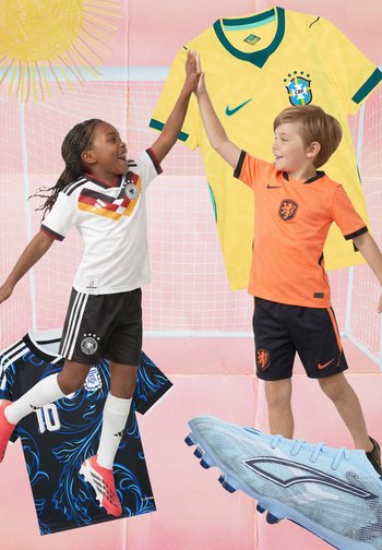 Deux enfants en tenue de football sautent et se tapent dans la main devant des maillots surdimensionnés, un filet de football et un grand crampon bleu sous un soleil éclatant.