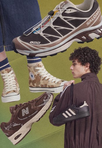 Des baskets variées comprenant Salomon, Converse camo montantes, New Balance et Adidas noires tenues par un jeune homme aux cheveux bouclés.