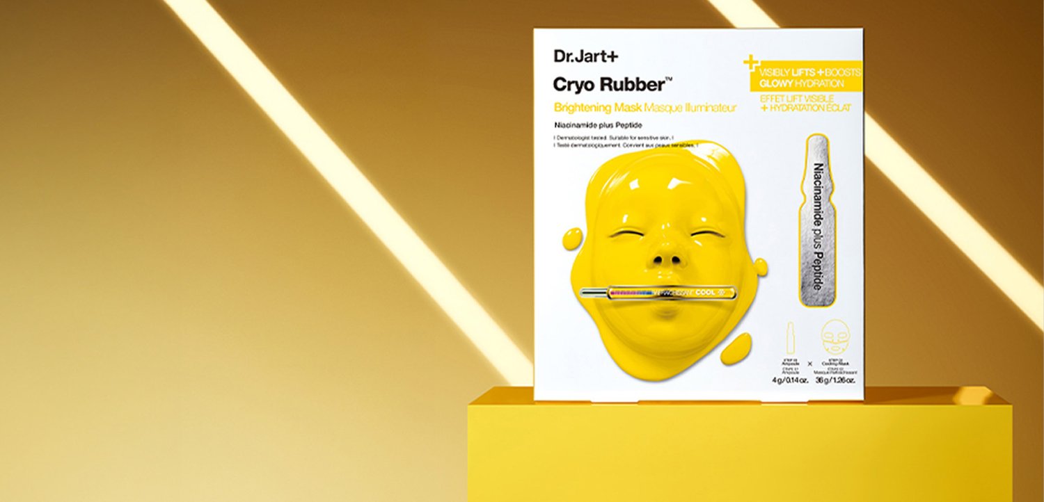Emballage du masque Dr.Jart+ Cryo Rubber Brightening Mask montrant un masque facial jaune brillant avec un tube argenté traversant les lèvres sur un piédestal jaune.