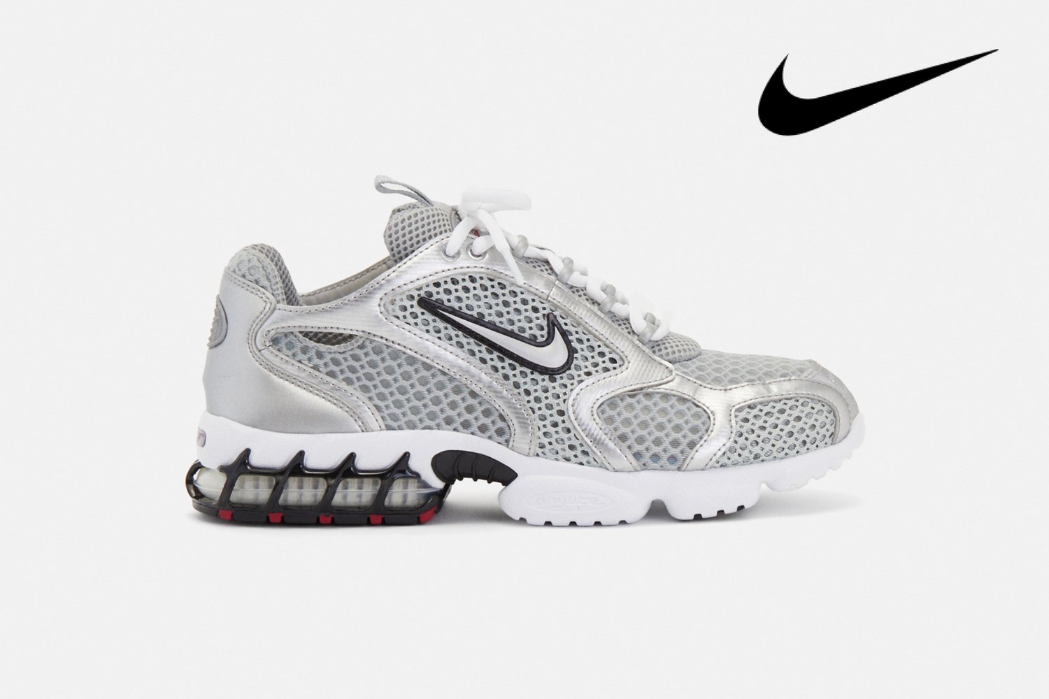 Zilveren Nike-sneaker met netstructuur en zichtbare demping, zijaanzicht, gepresenteerd tegen een effen witte achtergrond.