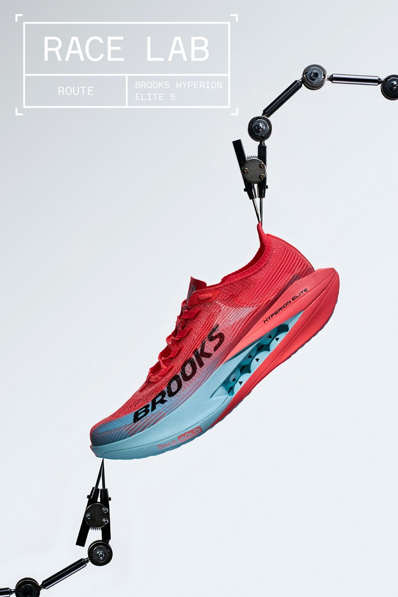 Chaussure de running Brooks Hyperion Elite 5 rouge et bleue suspendue par des bras mécaniques noirs sur un fond gris avec le texte Race Lab.