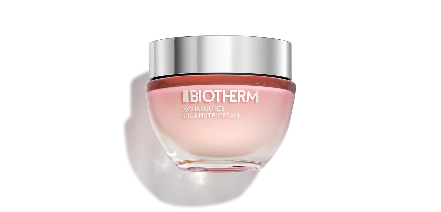 Ronde glazen pot van Biotherm Aquasource Cica Nutri Cream met een zilveren deksel, met een zacht roze verloop, tegen een witte achtergrond.