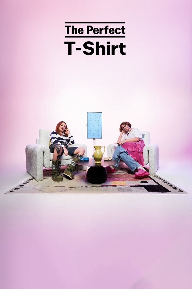 Twee personen zitten op pluche witte banken tegen een roze achtergrond. Een blauwe display staat op een zwarte tafel met een gele vaas.