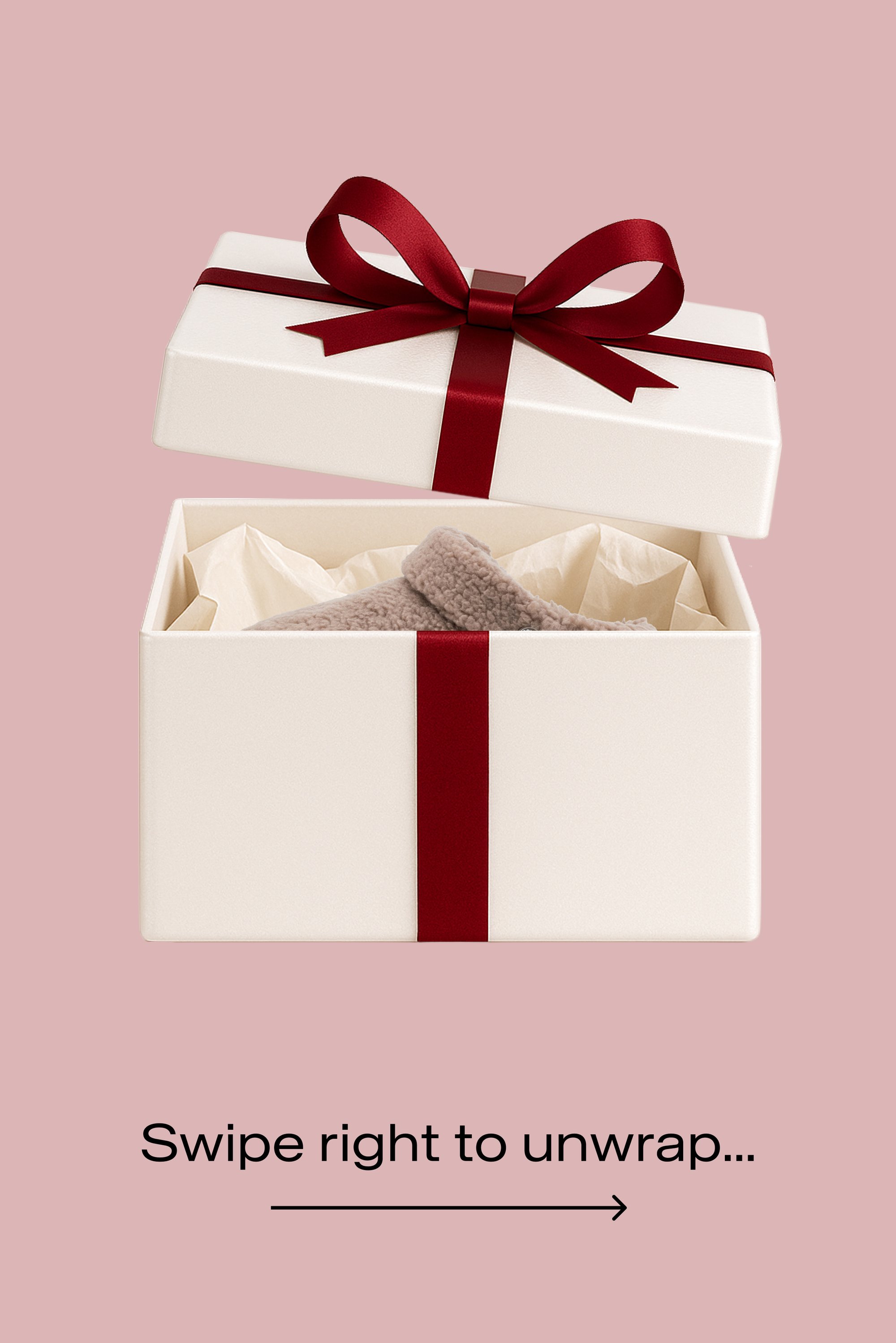 Weißer Geschenkkarton mit rotem Band und Schleife, der Deckel ist angehoben, um beiges Seidenpapier und ein gefaltetes, weiches beiges Kleidungsstück im Inneren zu zeigen.