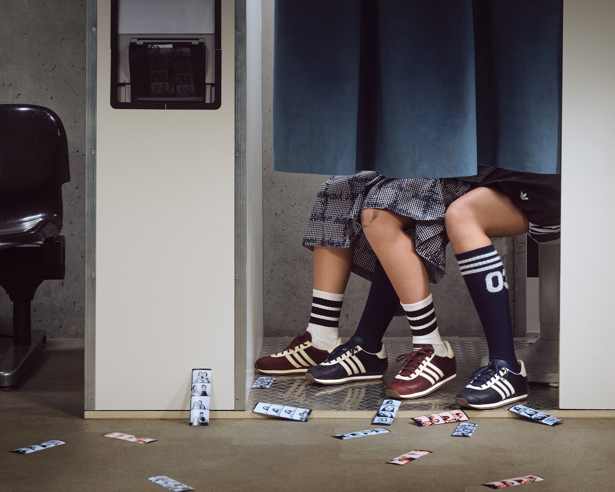 Twee mensen zitten in een kleedhokje, met hun benen zichtbaar. De één draagt een gebloemde rok en gestreepte sokken, de ander draagt shorts en gestreepte kniekousen. Filmstrips liggen verspreid op de vloer.