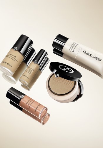 Cinq produits de maquillage Giorgio Armani : deux fonds de teint liquides dans des flacons transparents, un tube de primer, une poudre compacte et un highlighter avec une finition givrée.