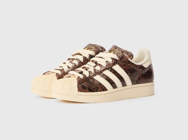 Καφέ αθλητικά παπούτσια με σχέδιο φιδιού, λευκές ρίγες, υφασμάτινη επάνω επιφάνεια, εκρού κορδόνια και λαστιχένια μύτη τύπου κέλυφος. Κλασικός σχεδιασμός χαμηλού προφίλ.