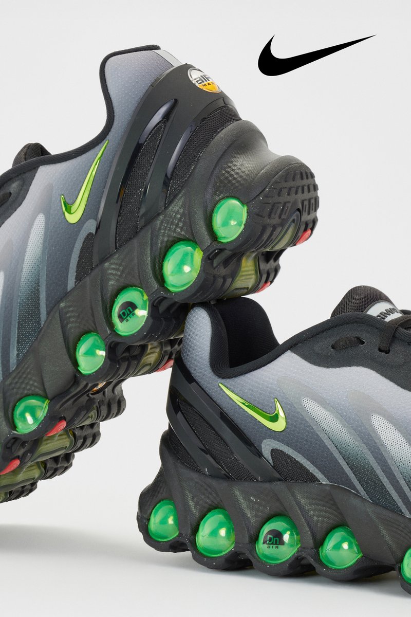 Grijze en zwarte Nike sneaker met een kenmerkende groene zool, opvallend swoosh-logo en een gestructureerd bovenwerk.