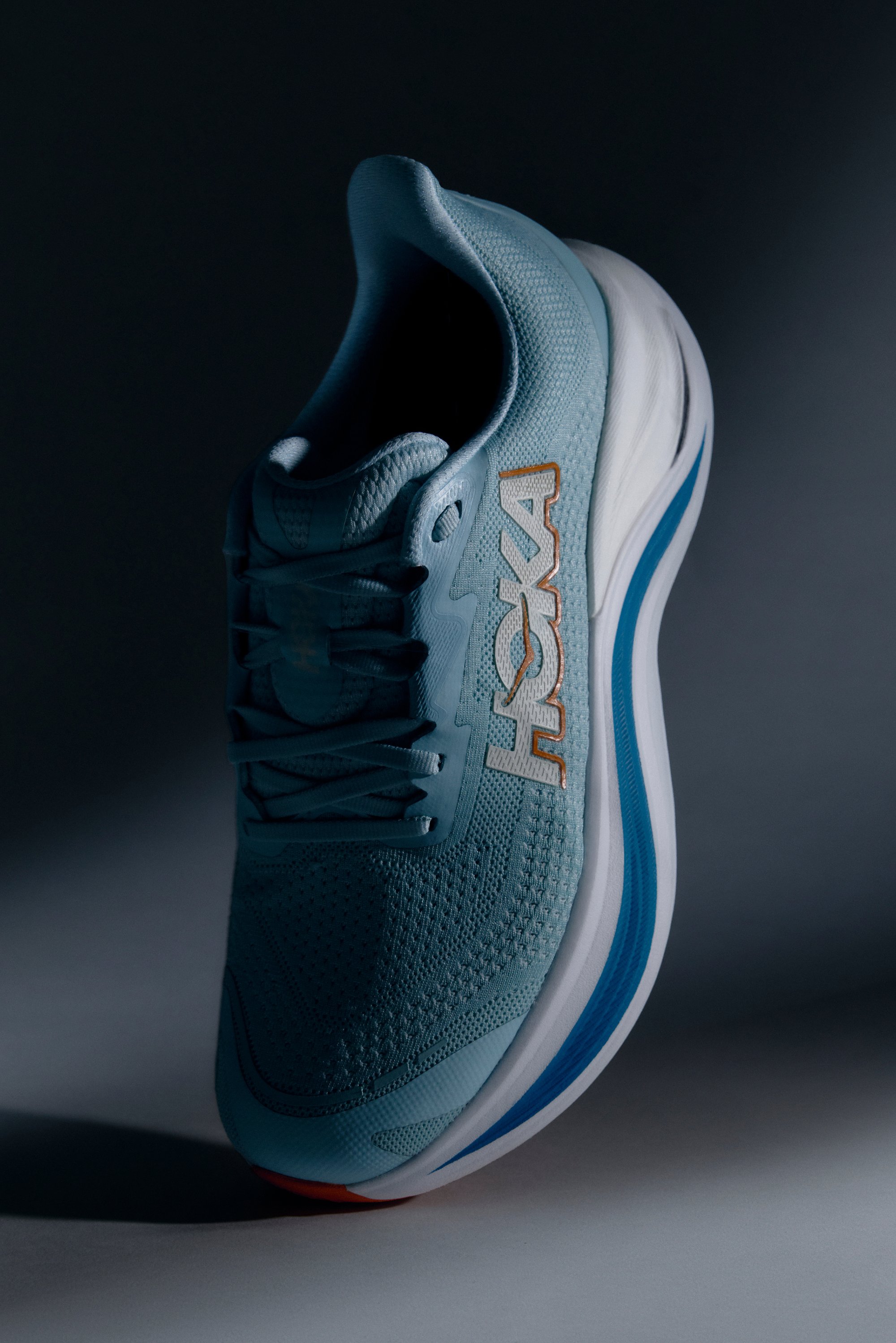 Hellblaue Sportschuh mit Netzobermaterial und strukturiertem Design, mit HOKA-Logo, weißer Zwischensohle und blauen Außensohlenelementen.