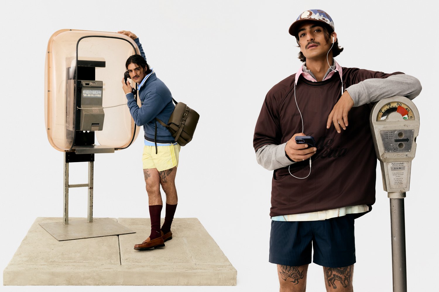 Man in gele shorts en blauwe trui gebruikt een telefooncel, terwijl een andere man in een bruine shirt zijn telefoon controleert naast een parkeermeter.