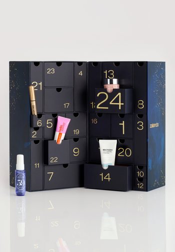 Black advent calendar with gold numerals and a starry design. Contains various beauty products in compartments, showcasing diverse packaging.