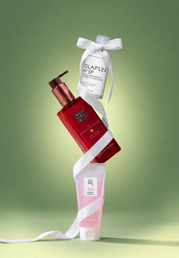Trois produits capillaires et soins de la peau sont disposés verticalement sur un fond vert, reliés par un ruban blanc.