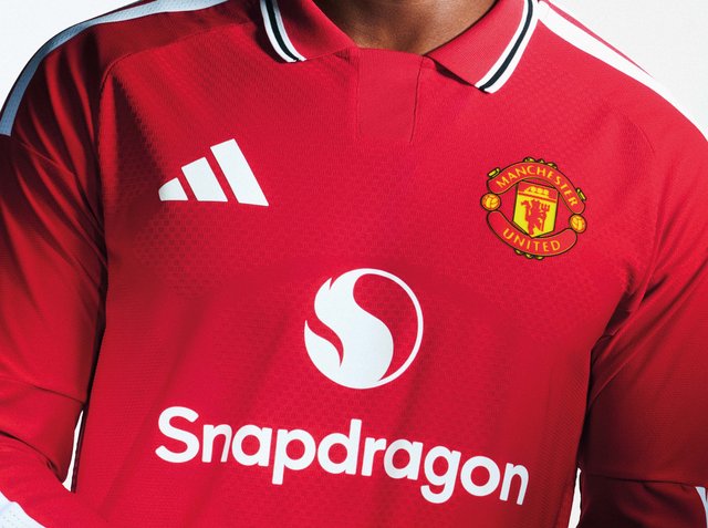 Rotes Manchester United Fußballtrikot mit weißem Snapdragon-Sponsorlogo und Adidas-Logo auf der Brust, getragen von einer Person.