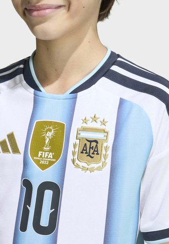 Personne portant le maillot de football de l'Argentine avec des rayures bleu clair et blanches, badge des champions du monde FIFA 2022, logo de l'AFA, et numéro 10.