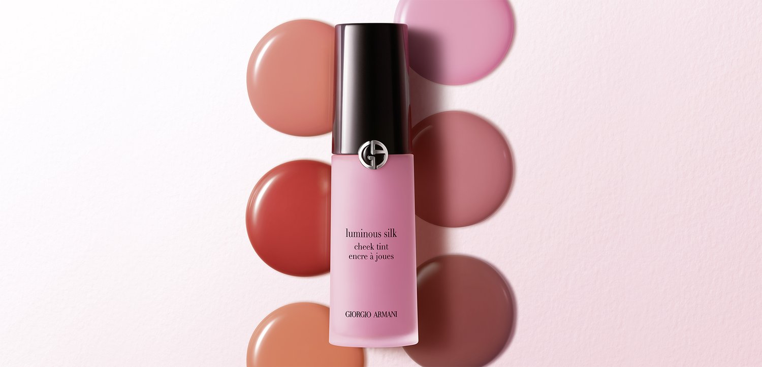 Flaske med Giorgio Armani Luminous Silk kinderødme centreret over seks cirkulære prøver af blush nuancer på en lys pink baggrund.